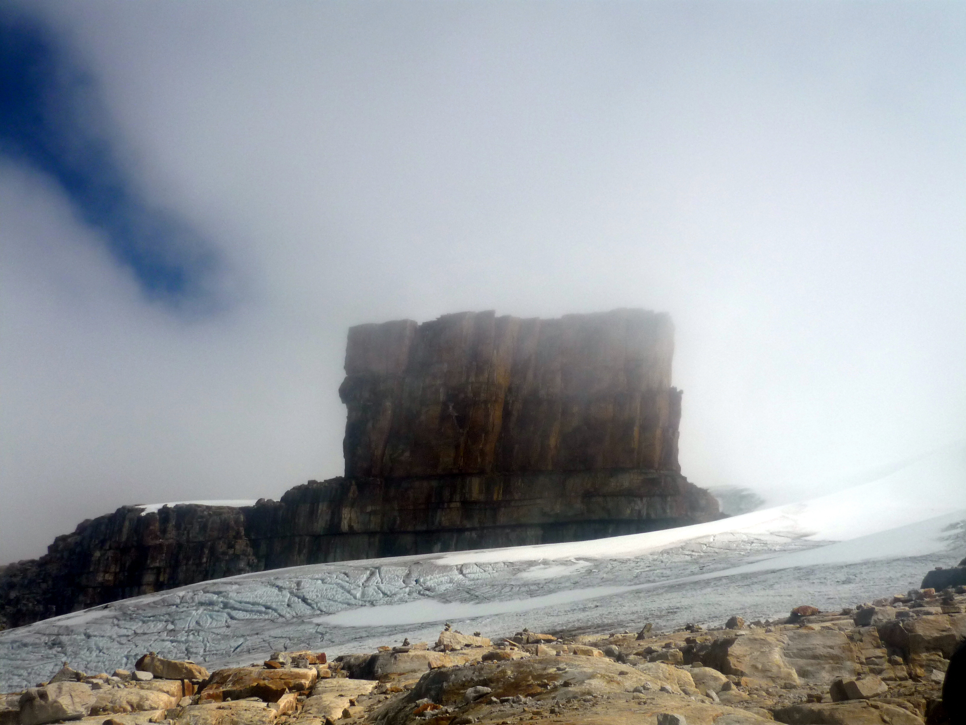 Rock formation emerging from mist and glacier